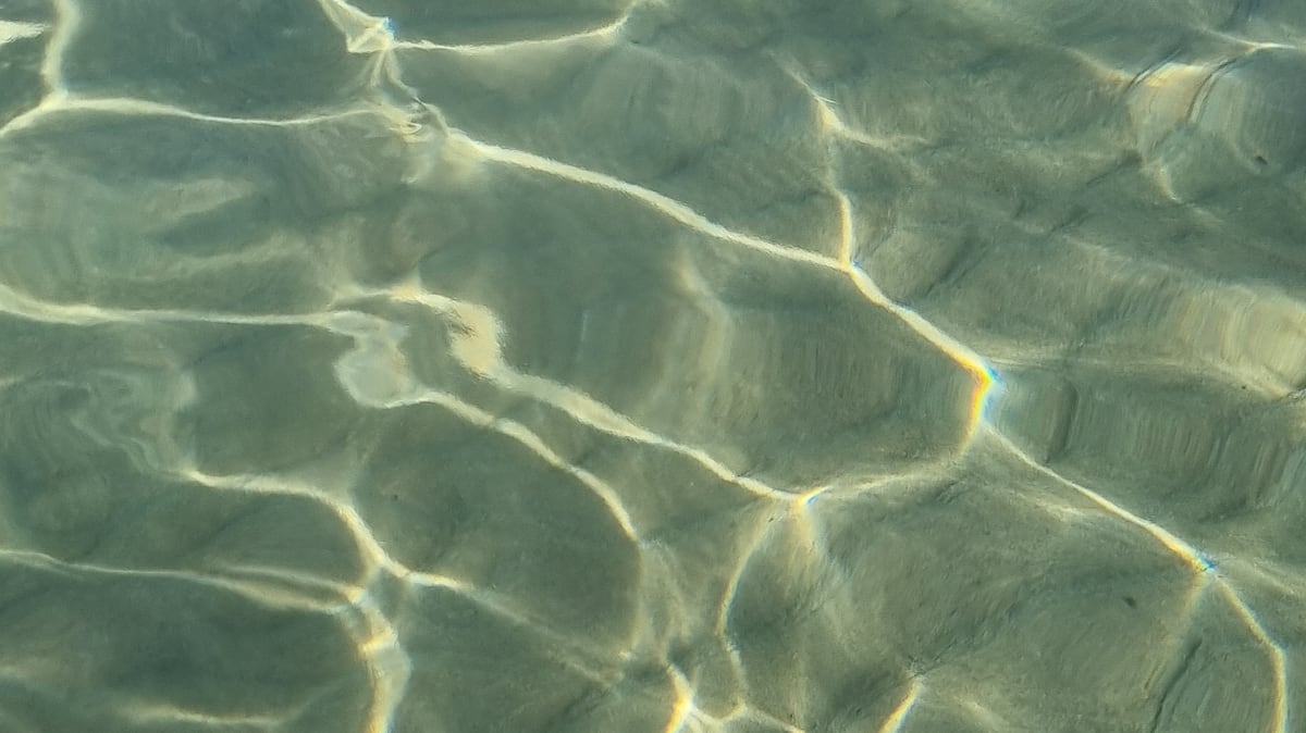 Lichtreflexe auf klarem, flachem Meerwasser in der Mani