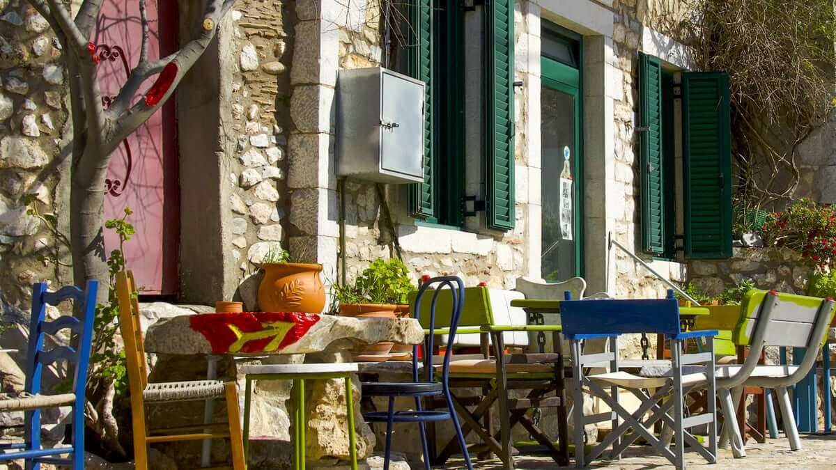 Traditionelle Taverne in der Mani mit bunten Stühlen und grünen Fensterläden