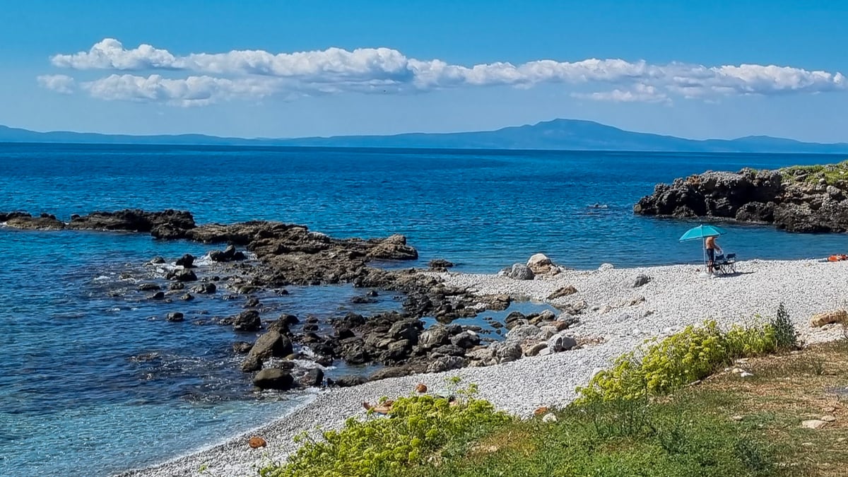 Weißer Kiesstrand in der Mani mit blauem Meer und Felsen